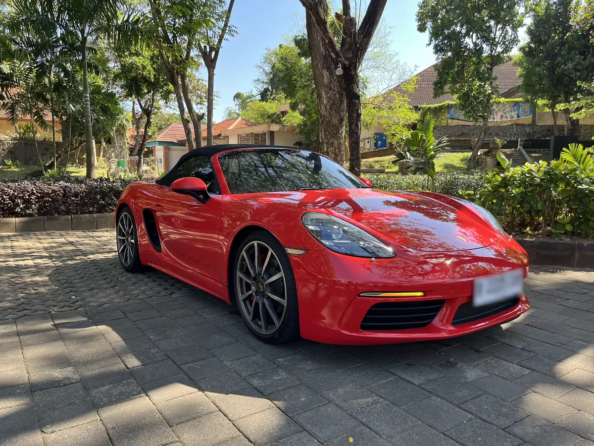 A red Porsche convertible from the Bali Travel Shop fleet, parked in a tropical garden in Bali